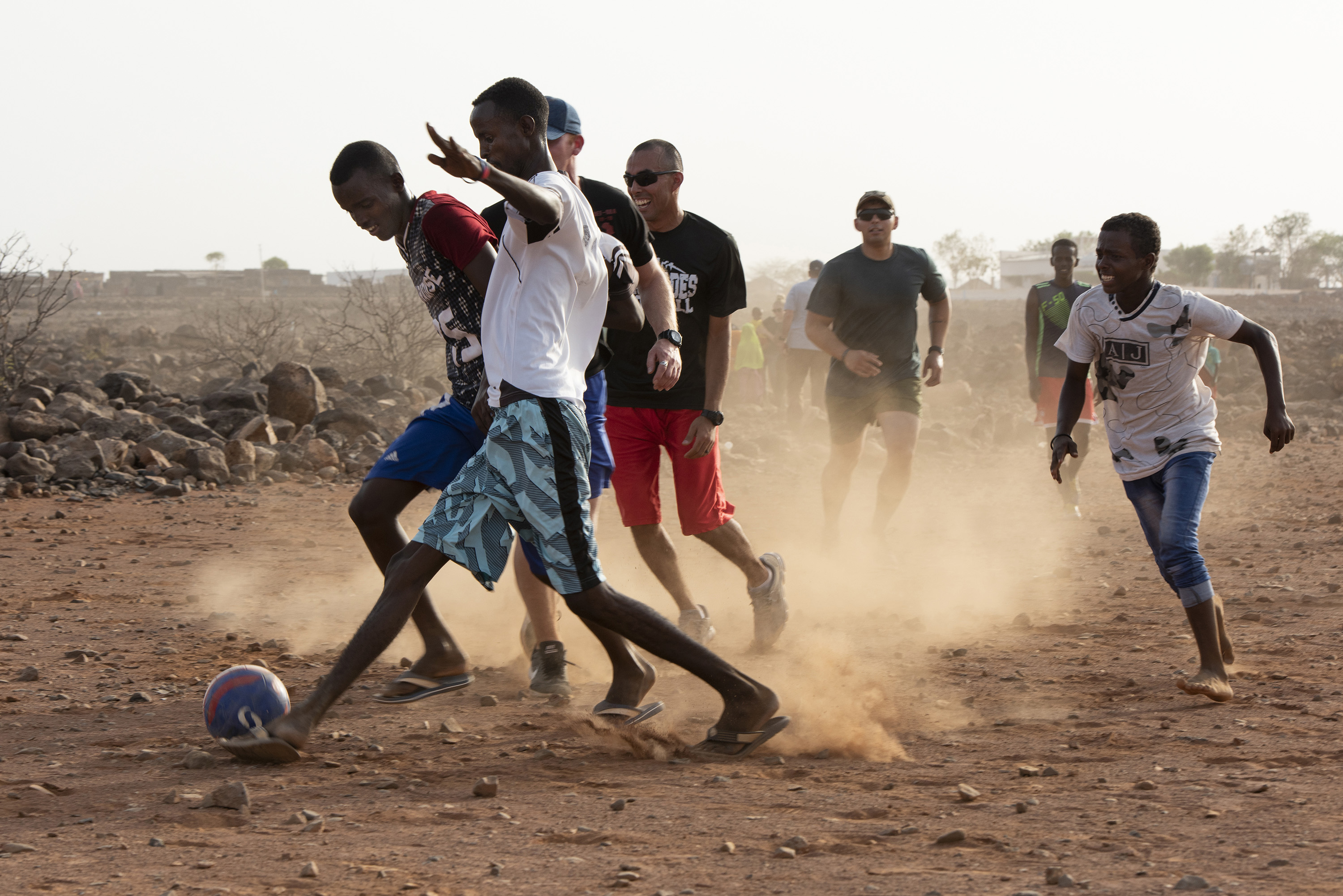 U.S. Service members assigned to Combined Joint Task Force - Horn of Africa participate in a friendly game of soccer with children from the nearby village, outside of Chebelley village, Djibouti, Aug. 3, 2018. Over 30 Soldiers and Airmen volunteered for the outreach event organized by the 404th Civil Affairs Battalion. (U.S. Air National Guard photo by Master Sgt. Sarah Mattison)